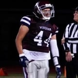 Football player wearing dark Windham jersey number 44 with official standing nearby on field