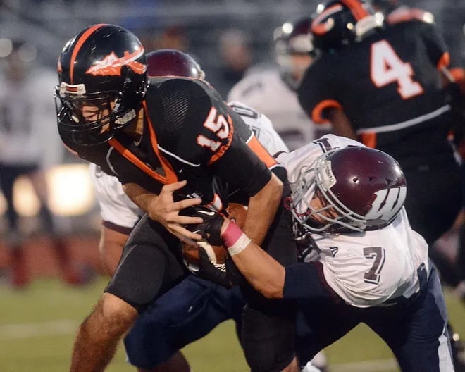 Football players tackling opponent during night game