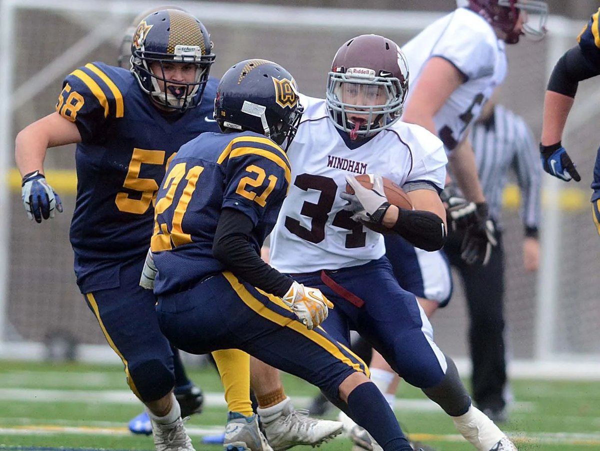 Youth football game showing defender in blue and gold uniform pursuing ball carrier in white uniform