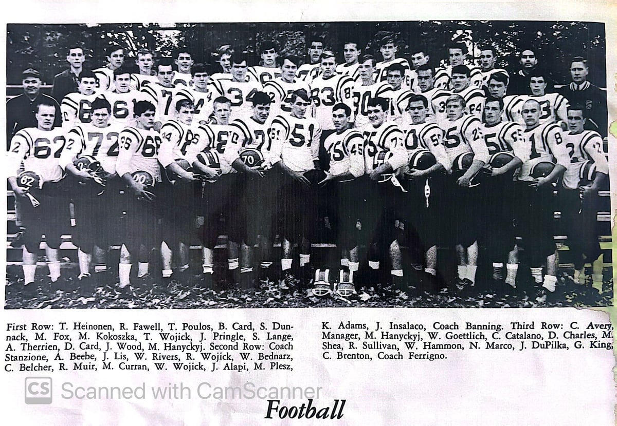Black and white vintage football team photo with players in numbered jerseys and coaches standing in rows